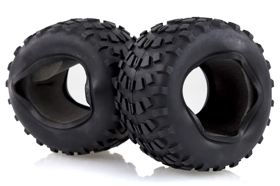 Two black rubber RC off-road tires with blocky tread patterns and grey foam inserts inside, set against a white background.