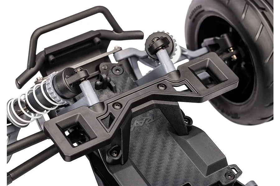 Close-up of the front suspension and chassis components of a Traxxas RC stadium truck, showing the shock towers, bumper, and front wheel.