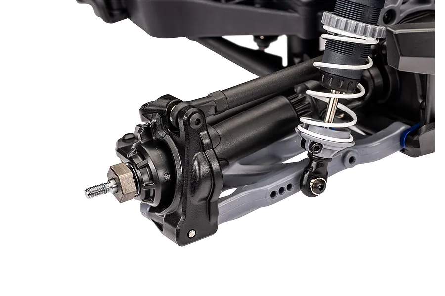 Close-up of the rear suspension and wheel hub assembly of a Traxxas RC monster truck, showing the shock absorber, control arm, and axle nut.
