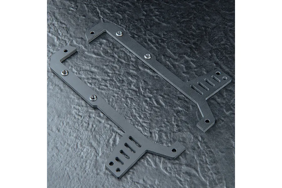 Two black FRP upper deck chassis plates for an RC car, featuring mounting holes and slots, displayed on a textured dark surface.
