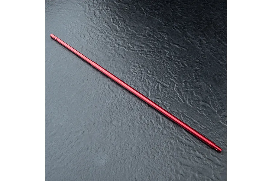A red anodized aluminium centre driveshaft for an RC car, shown against a dark textured background.