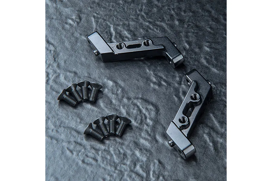 Two black anodized aluminium bulkhead parts for an RC car, accompanied by eight small black countersunk screws, arranged on a dark textured surface.