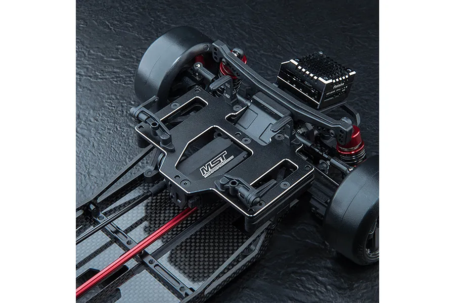 A black MST aluminium battery and servo mounting plate installed on an RC drift car chassis.