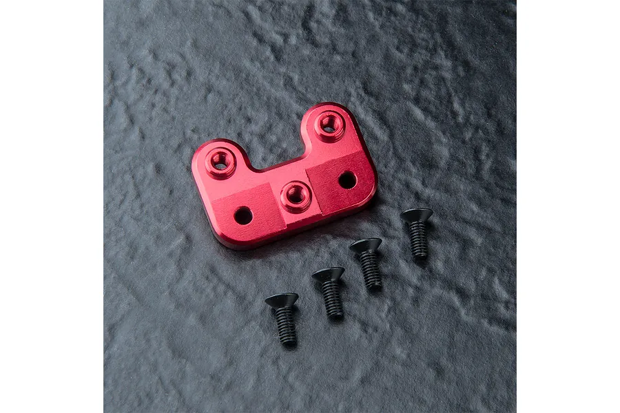 A red anodized aluminium steering arm mount for an RC car, accompanied by four black flat-head screws on a dark textured surface.