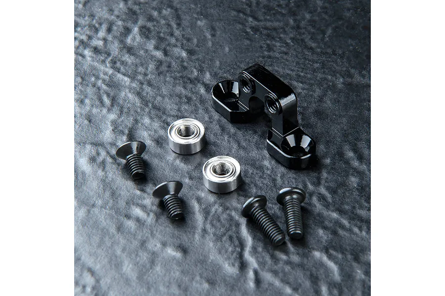 MST aluminium transmission vibration suppressor in black, including two ball bearings and four black countersunk screws on a dark textured surface.