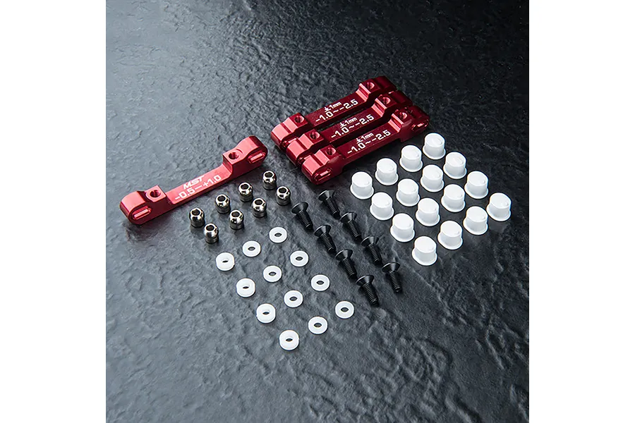 MST red aluminium suspension arm mount set including four metal mounts, screws, plastic spacers, and bushings on a dark textured surface.