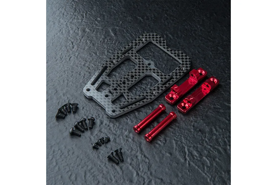MST carbon fiber front suspension arm mount set with red anodized aluminum components and black screws on a textured black surface.