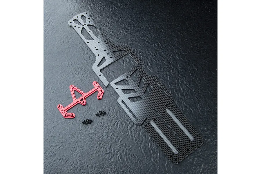 MST carbon fiber lower chassis deck components with a red anodized aluminum brace and small black screws on a textured black surface.