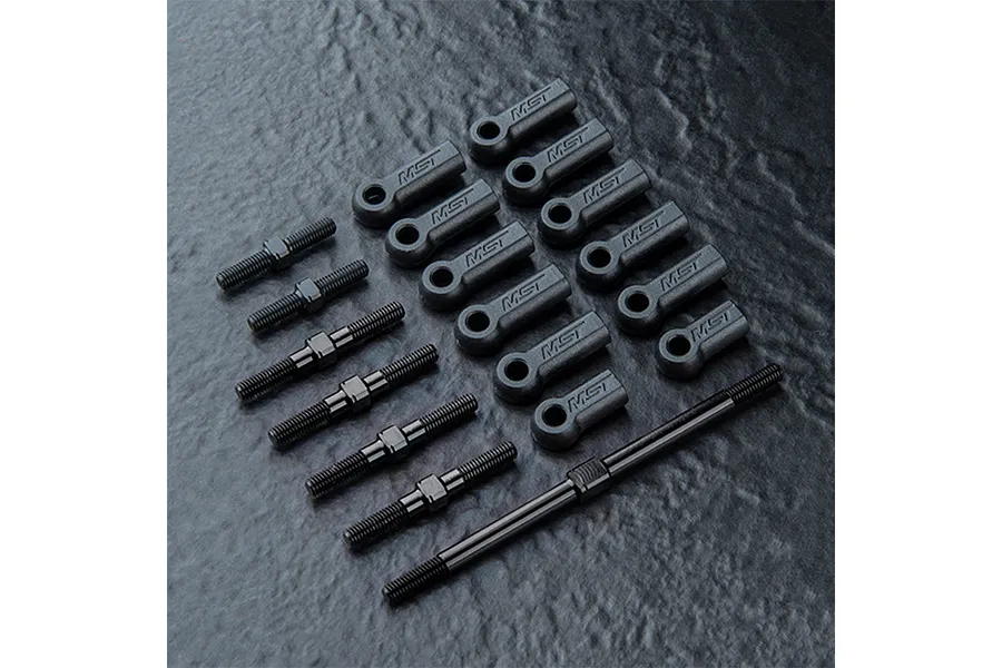A set of black MST RC turnbuckles and rod ends arranged on a dark textured surface.