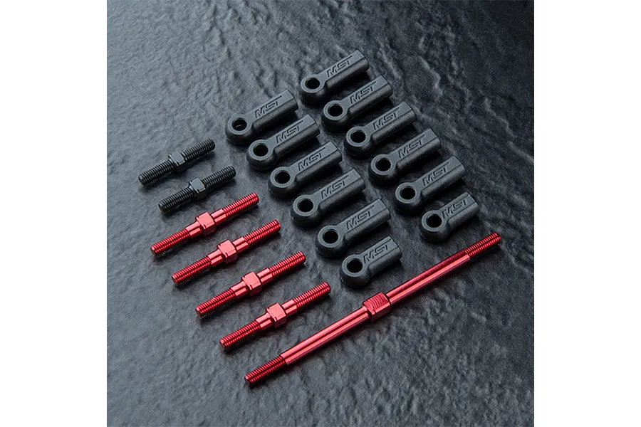 A set of MST RC car turnbuckles including red anodized aluminium rods and black plastic ball ends arranged on a dark textured surface.