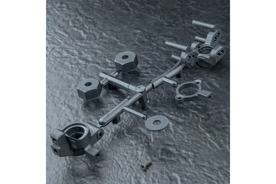 A black plastic parts tree containing RC car wheel hexes, steering hubs, and washers on a textured dark surface.