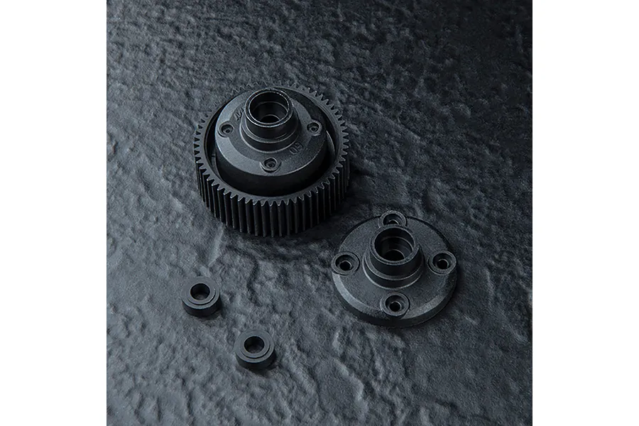 MST wide version bevel gearbox case components including a gear housing, a cover plate, and two small bushings on a dark textured surface.