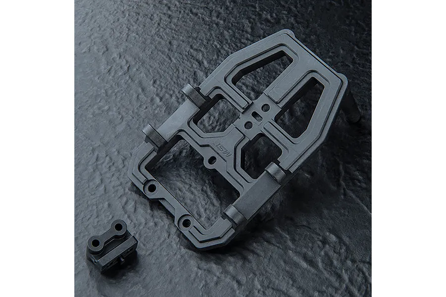 A black MST front head set component for an RC car chassis, shown on a dark textured surface.
