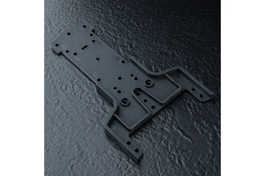 A black MST front lower deck chassis part for an RC car, shown from an overhead angle on a textured black surface.