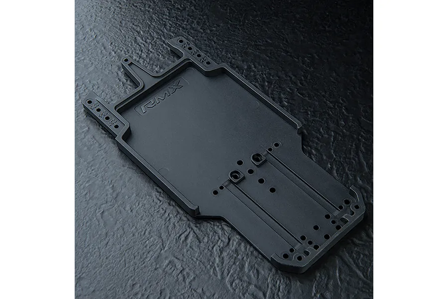 Black MST RMX series RC car rear lower deck chassis plate on a dark textured surface.