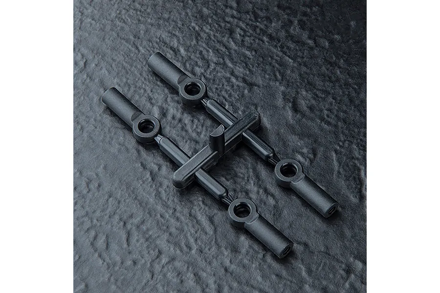 Four black plastic RC rod ends attached to a sprue tree on a dark textured background.