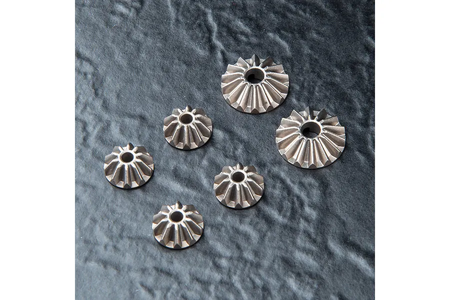 A set of six metal differential bevel gears of varying sizes arranged on a dark textured surface.