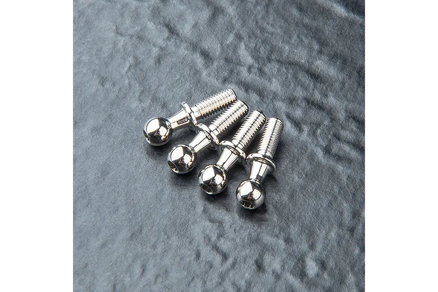Four silver-colored metal ball studs arranged in a row on a dark, textured surface.