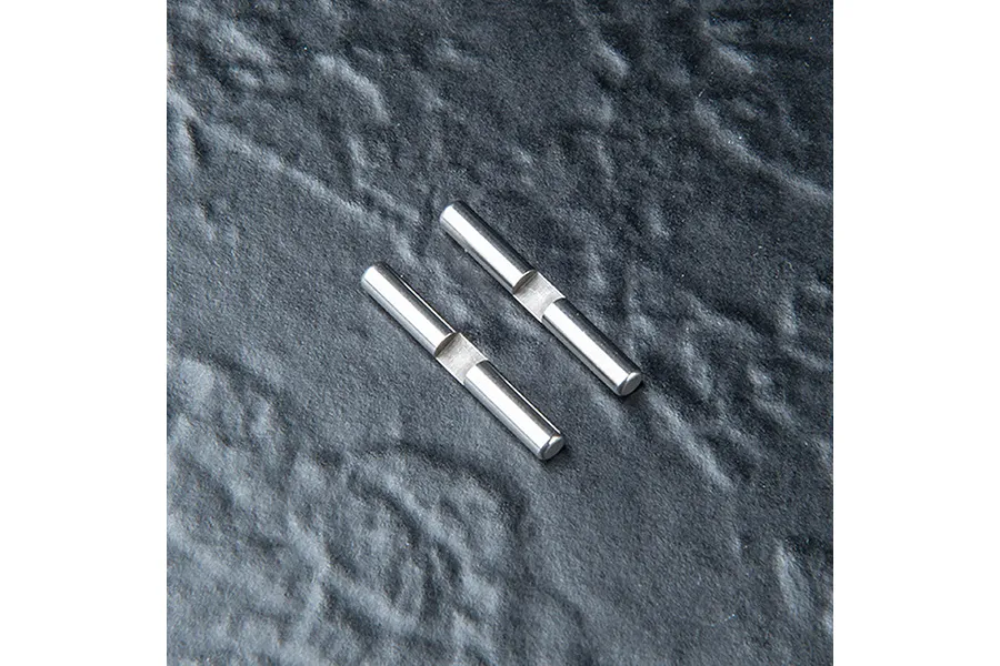 Two silver metal drive pins with a flat notch in the center, positioned diagonally on a dark textured surface.