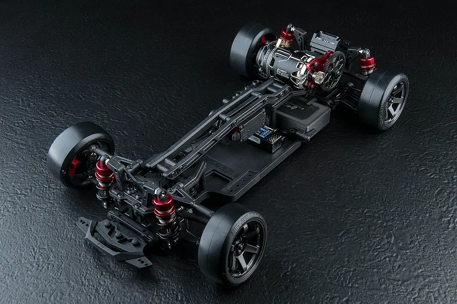 High-angle studio shot of an assembled MST RMX 4 S Pro RC drift car chassis on a black textured background.