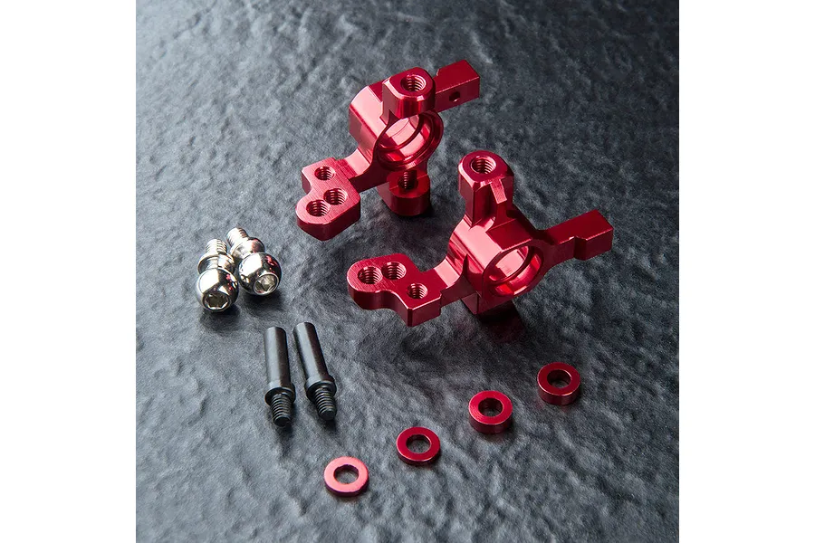 Two red anodized aluminium MST ATK V3 steering hubs with included screws, spacers, and pins on a textured dark surface.