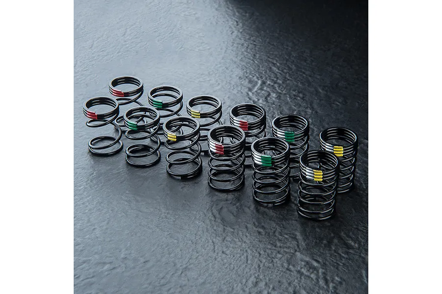 A set of black MST competition drift springs with various coloured markings on a dark textured surface.