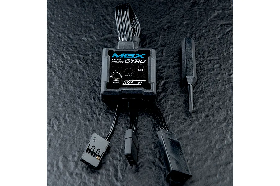 MST MGX Drift Racing Gyro unit with attached wiring harness and a small adjustment screwdriver on a textured black surface.