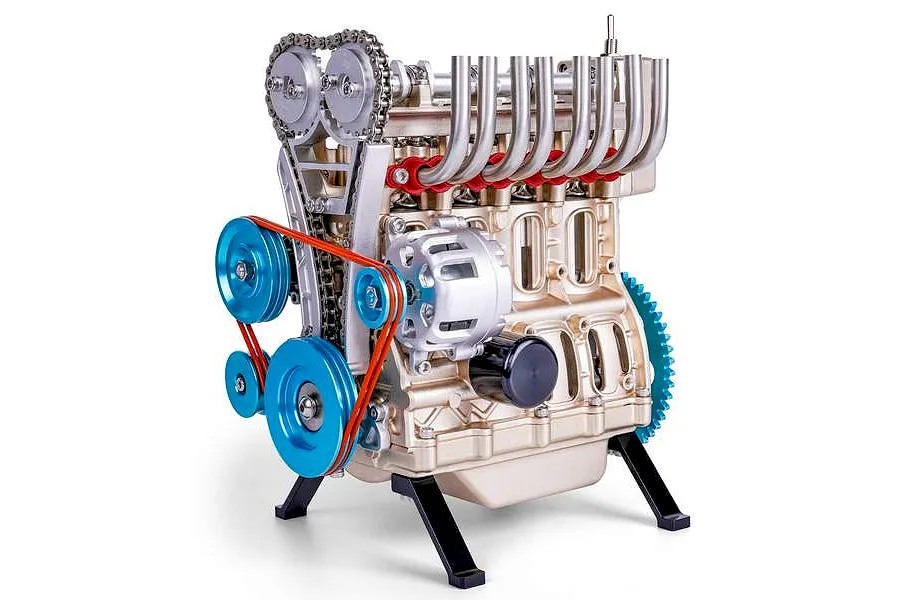 A detailed metal model kit of a four-cylinder engine with gold-toned engine block, blue pulleys, and red drive belts, mounted on a black stand.