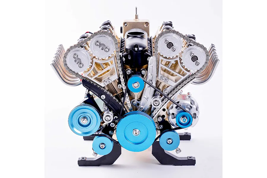 A detailed front-facing view of the Teching DM118 V8 engine model kit, showing metallic gears, chains, pulleys, and a black intake manifold.
