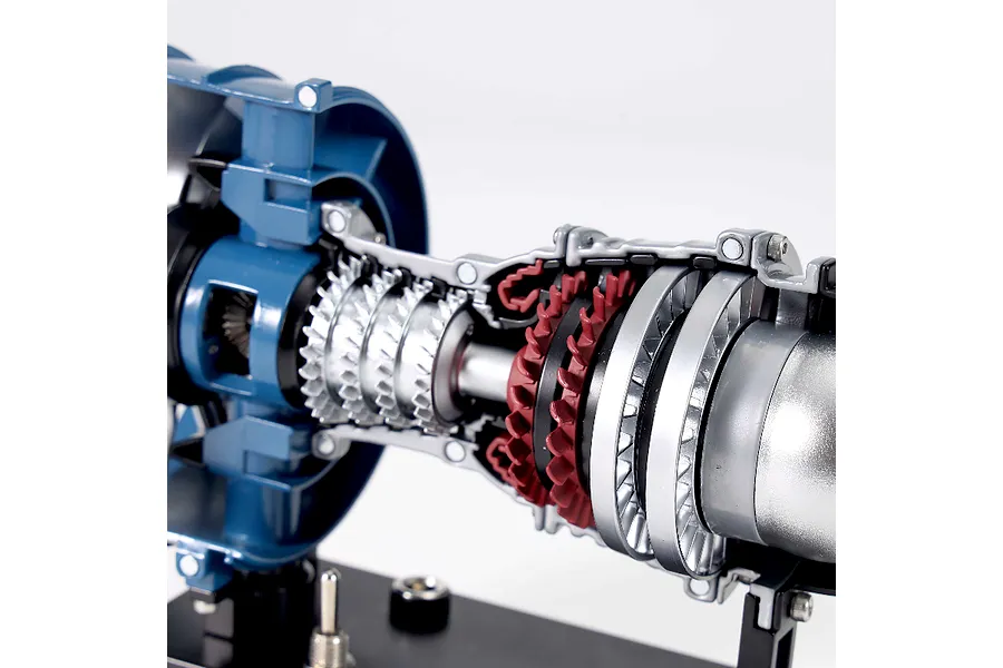Close-up of a Teching DM122 turbofan engine model showing internal turbine blades, silver and red components, and a blue outer casing on a black stand.