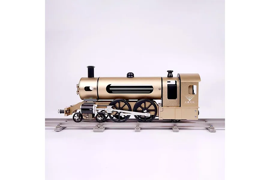 Side view of a gold-coloured Teching DM221 steam train model kit sitting on a metal track against a white background.