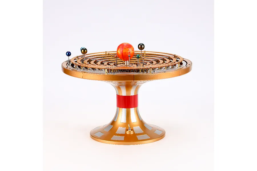 A Teching DM405 solar system model kit featuring a central sun surrounded by concentric gear-driven orbits with small planetary spheres on a gold pedestal.