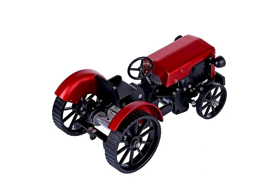 A high-angle studio shot of the Teching DM616 metal tractor model kit, featuring a red hood and fenders with a black chassis and wheels.