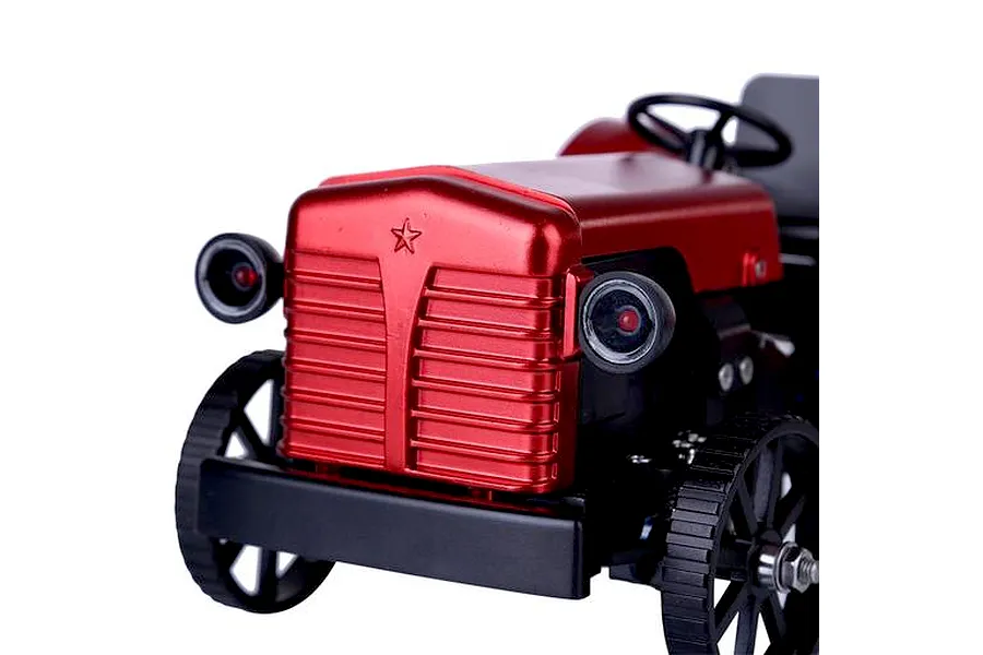 Close-up of the front of a red metal Teching DM616 RC tractor model kit showing the grille, headlights, and front wheels.