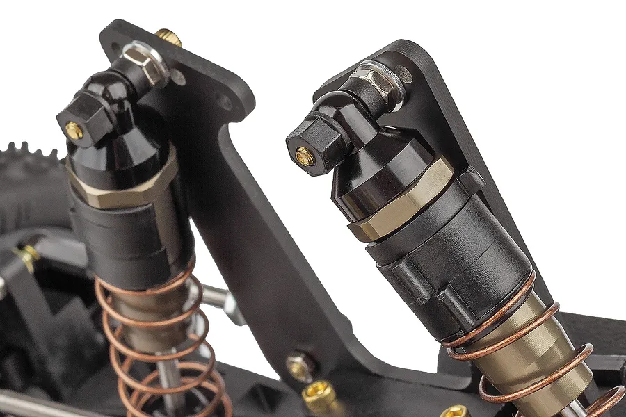 Close-up of the front suspension and shock absorbers on a Team Associated RC10 RC buggy, showing black shock bodies and copper-coloured springs.
