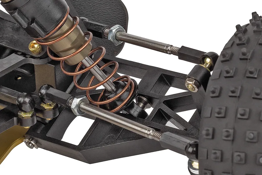 Close-up of the front suspension and steering assembly on a Team Associated RC10 buggy, showing the shock absorber, turnbuckles, and tire.