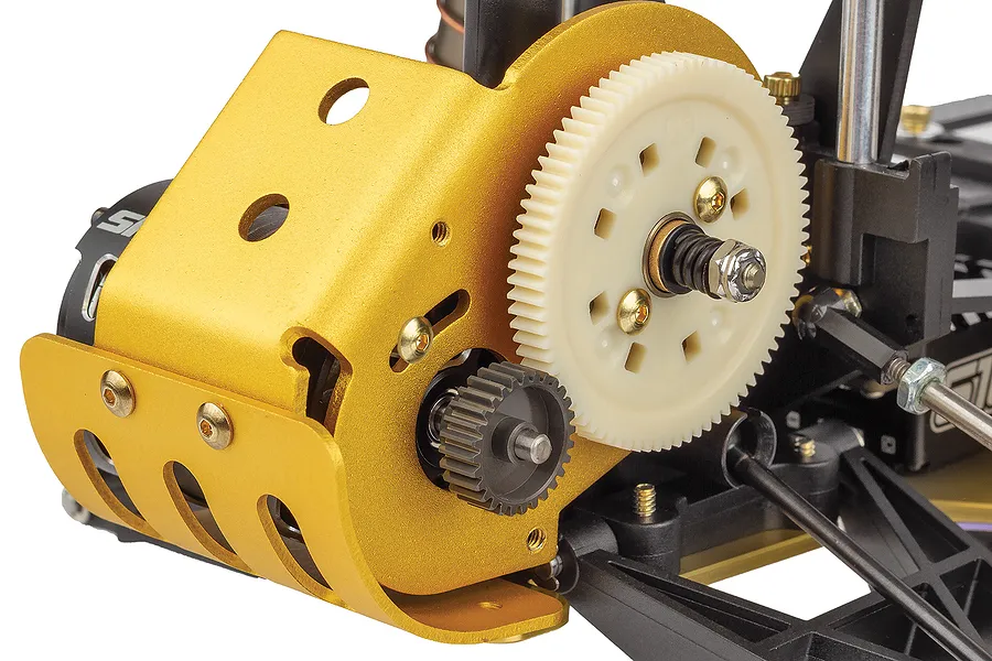 Close-up of the gold anodized motor mount and white spur gear on a Team Associated RC10 buggy chassis.