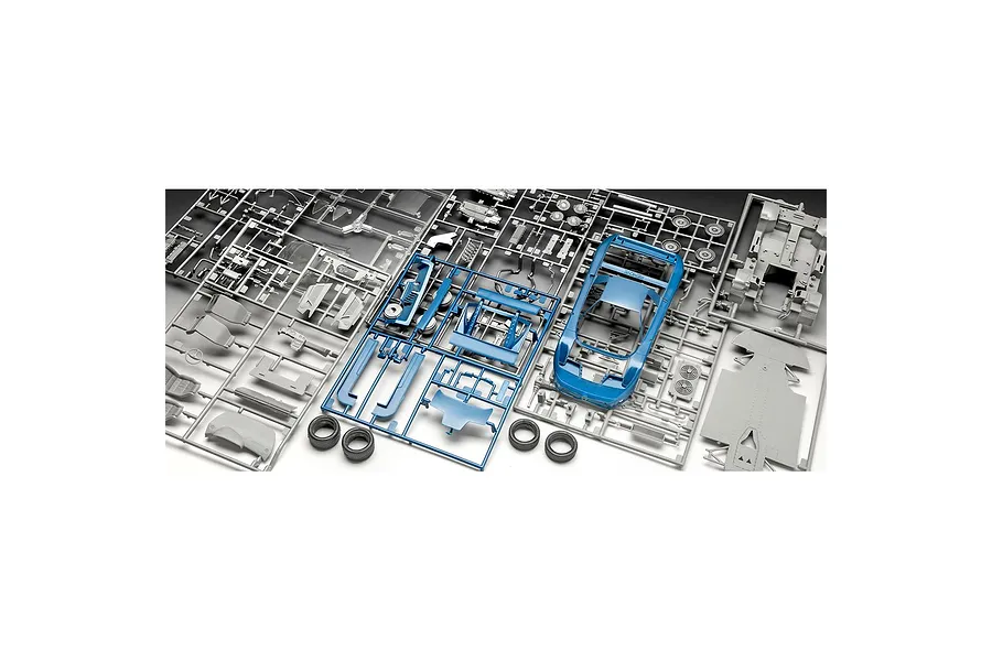 Plastic model kit sprues for a 1/24 scale Bugatti EB 110, featuring grey and blue components and four rubber tires on a white background.