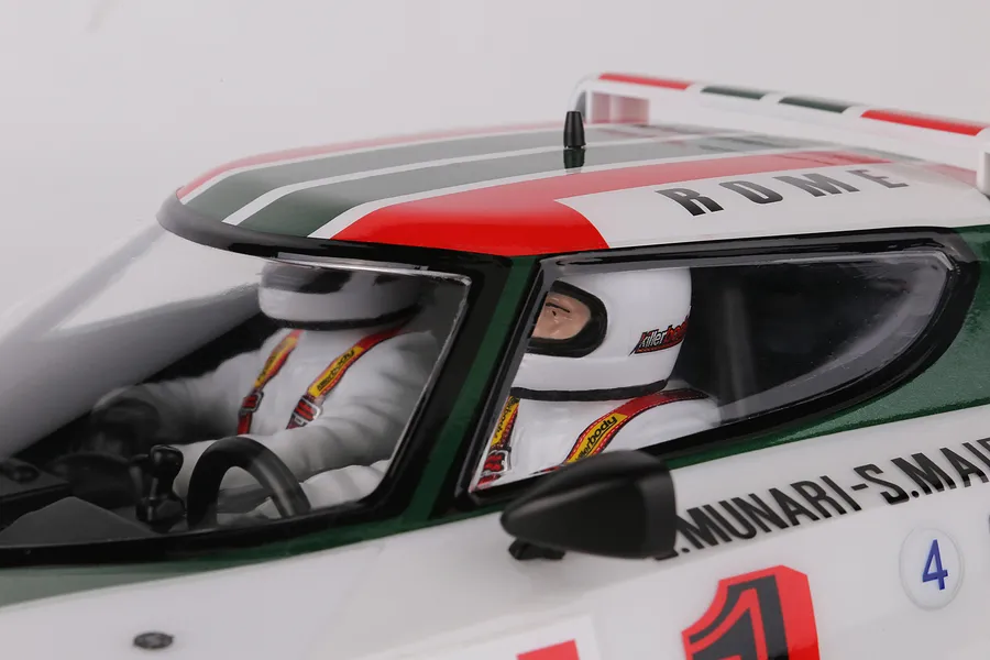 Close-up of the interior cockpit of a Killerbody Lancia Stratos RC car, showing two driver figures in white racing suits and helmets.