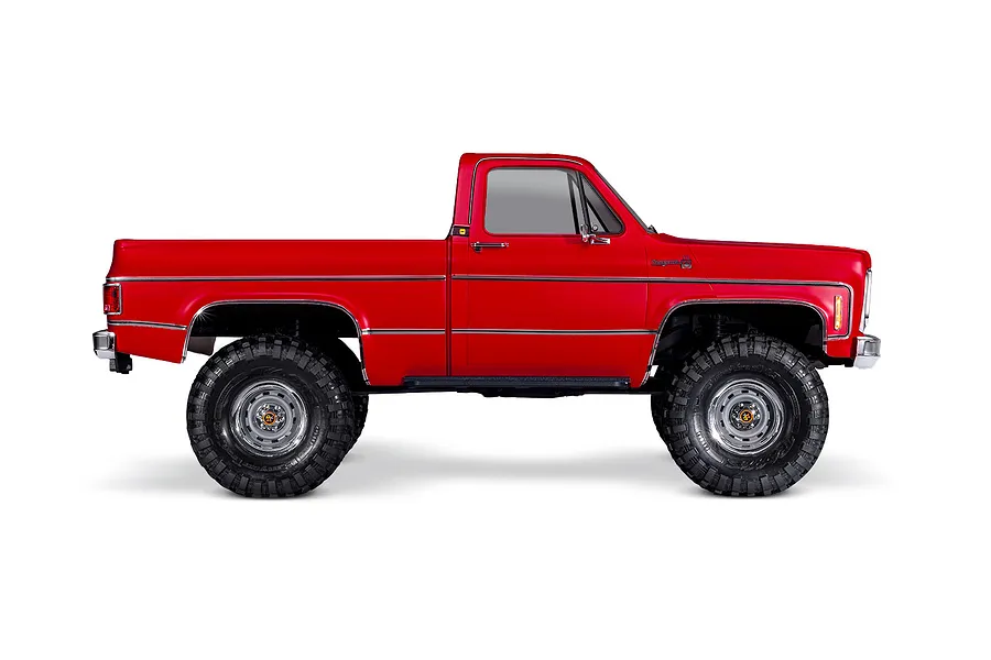 Side profile of a red Traxxas TRX-4 1979 Chevrolet Cheyenne K10 RC rock crawler truck on a white background.