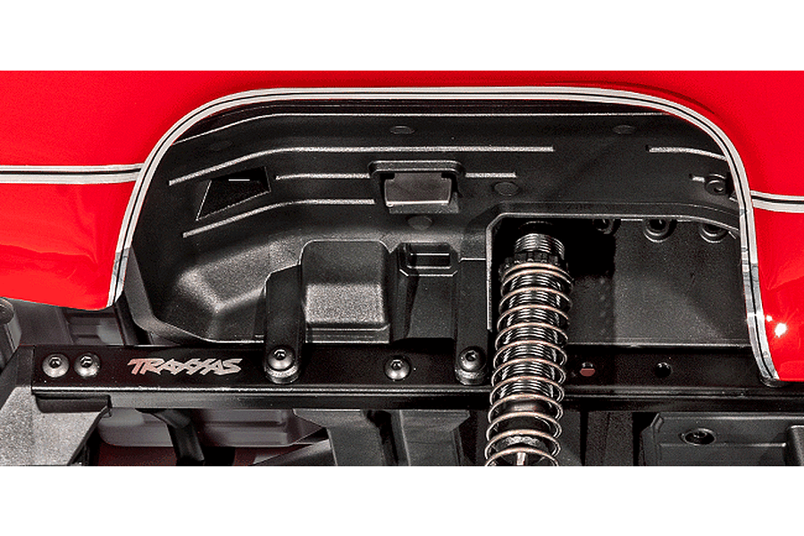 Close-up of the wheel well and suspension area of a Traxxas TRX-4 RC crawler, showing the inner fender, coil-over shock, and chassis rail.