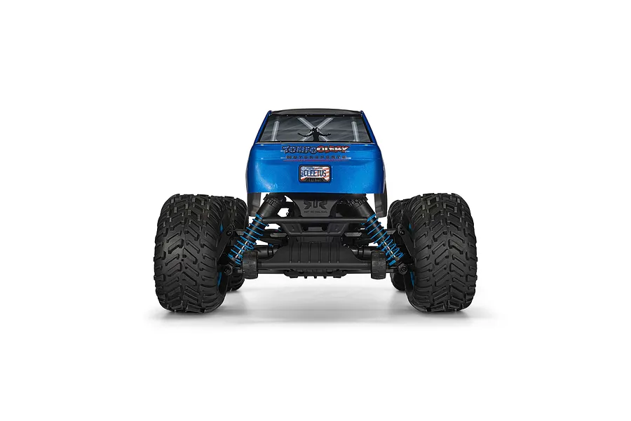 Rear view of the ARRMA Freedom Flyer RC monster truck showing the blue body, large knobby tires, and blue coil-over shocks against a white background.