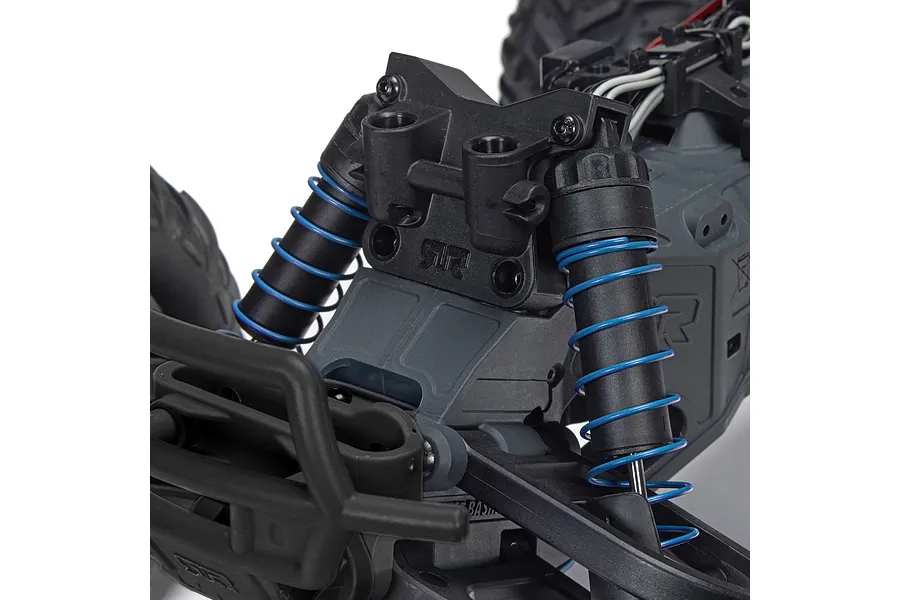 Close-up of the front suspension and shock absorbers on an ARRMA RC monster truck, featuring black plastic parts and bright blue coil springs.