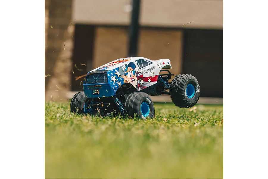 ARRMA Freedom Flyer RC monster truck performing a wheelie on grass with patriotic American flag-themed bodywork.