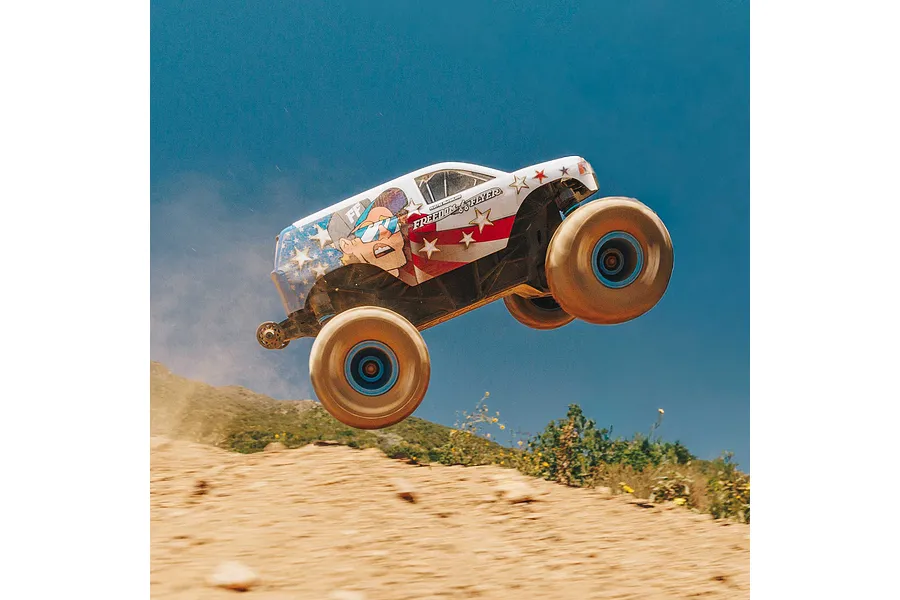 ARRMA Freedom Flyer Grom RC monster truck jumping in the air against a clear blue sky.