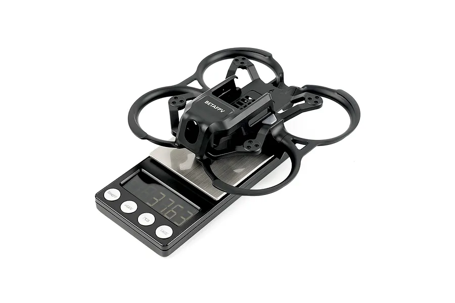A black BetaFPV drone frame sitting on a digital scale, showing the weight of the component.