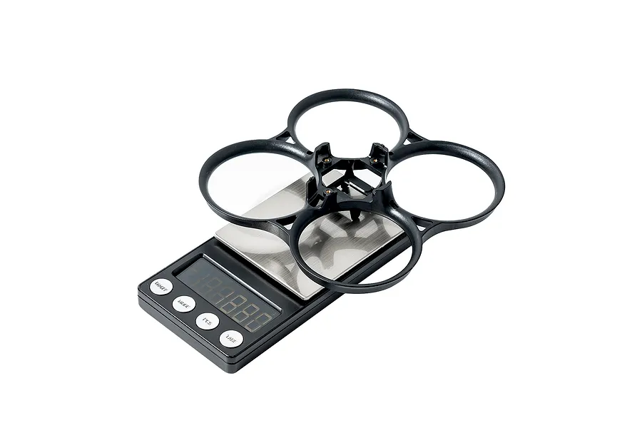 A black BetaFPV drone frame duct sitting on a digital scale against a white background.