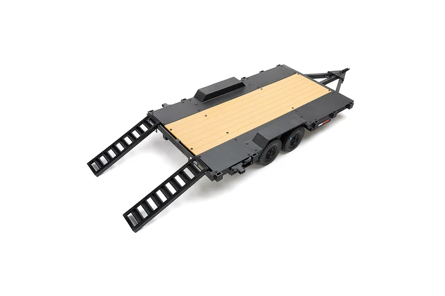 Axial 1/10 scale flat bed RC vehicle trailer with dual axles, black frame, and wood-look deck with two rear loading ramps extended.
