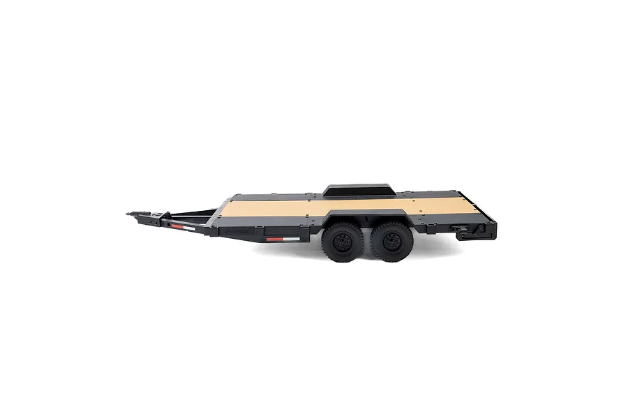 Side view of an Axial 1/10 scale flat bed vehicle trailer with a black frame, wooden deck, and dual axles on a white background.
