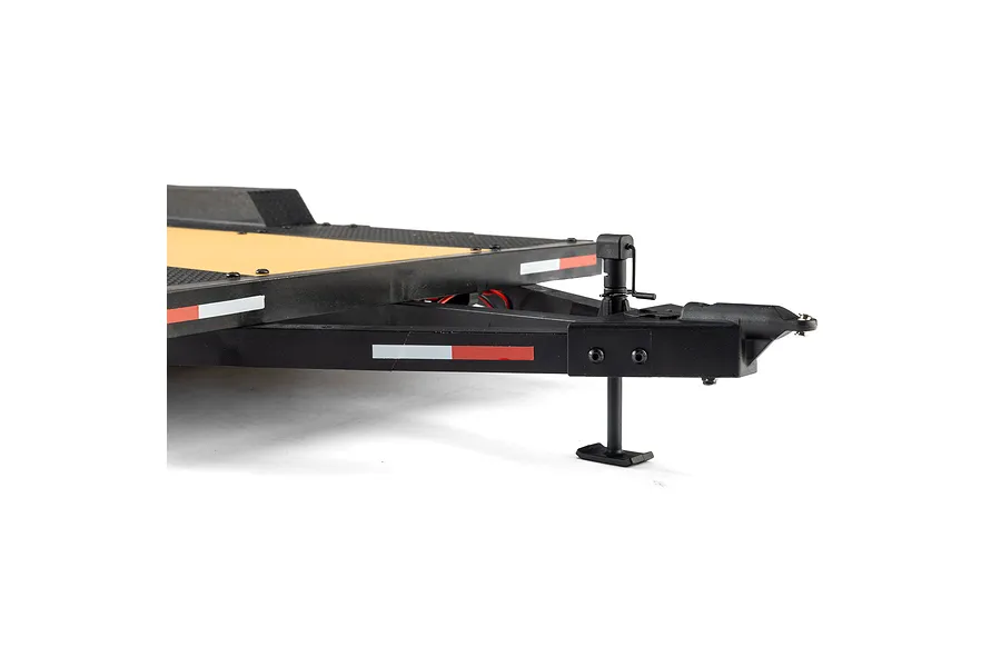 Close-up of the hitch and landing gear of an Axial 1/10 scale flat bed RC vehicle trailer, showing the black frame and yellow deck.